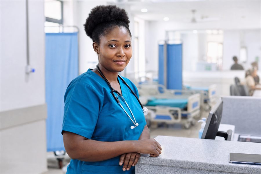 Nurse in teal scrubs at a hospital nurses station
